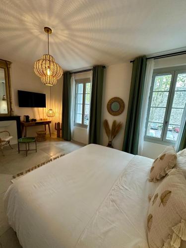 a bedroom with a large white bed and a chandelier at 27 côté remparts in Aigues-Mortes
