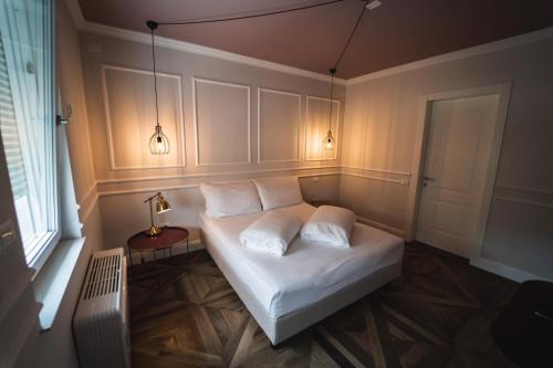a bedroom with a bed with white sheets and pillows at Locanda Gaudemus Boutique Hotel in Sistiana