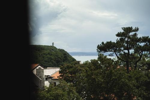 a view of the ocean and a house with trees at Locanda Gaudemus Boutique Hotel in Sistiana