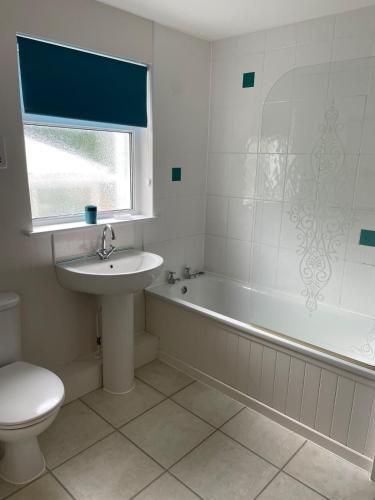 a bathroom with a sink and a tub and a toilet at Bryntivy - a cheerful stone cottage close to beach in Saint Dogmaels