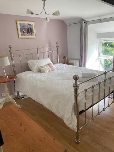 a bedroom with a large bed with white sheets at Bryntivy - a cheerful stone cottage close to beach in Saint Dogmaels