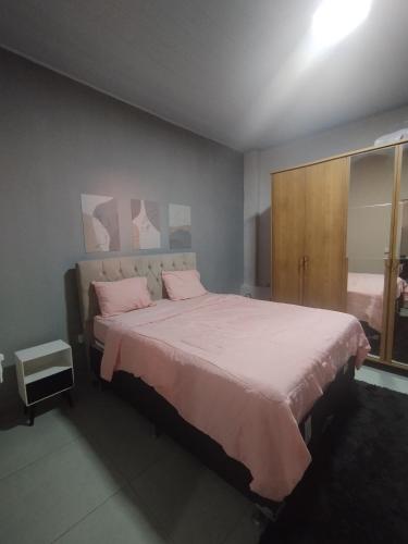 a bedroom with a large bed with pink sheets at Refúgio Dom Emanuel in Pirenópolis