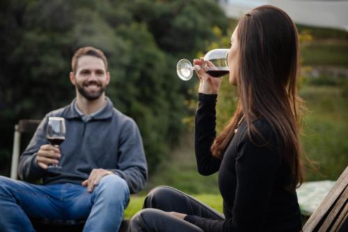 a man and a woman sitting on a bench drinking wine at Pousada Calza - Vale dos Vinhedos - Bento Gonçalves in Bento Gonçalves