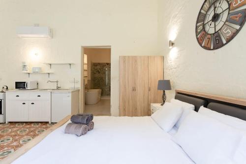 two beds in a room with a clock on the wall at BnBNova - Historic Valletta Duplex in Valletta