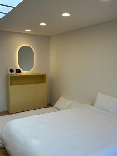 a bedroom with a large white bed and a mirror at Momo House in Gimhae