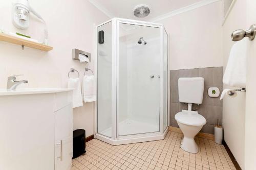 a white bathroom with a shower and a toilet at City Heart Motel Warrnambool in Warrnambool