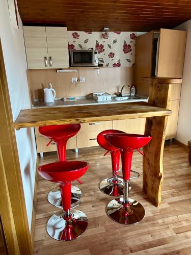 a kitchen with red bar stools in front of a counter at Drevený Raj Apartmán in Hrabušice