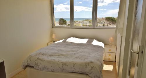 une petite chambre avec un lit et deux fenêtres dans l'établissement Appart 385, Port Nature 3 au village naturiste, au Cap d'Agde