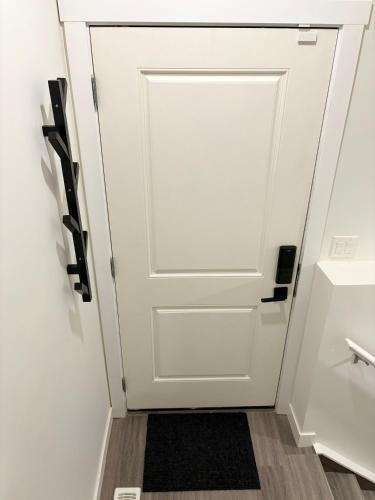 a white door in a room with a black rug at Coziest & Modern Basement Retreat East of Calgary in Chestermere
