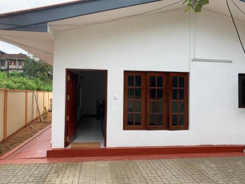 a white house with red doors and a hallway at Carmel Crown Villa in Hatton