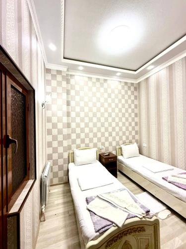 a small room with two beds and a tv at Yusuf Gold House in Samarkand