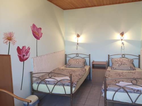 ハイドゥソボスローにあるPinczés Házの花が飾られた壁の客室内のベッド2台