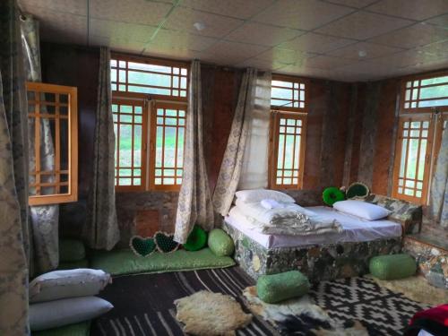 a bedroom with a bed in a room with windows at Bagh Rustum Guest House in Holshāl