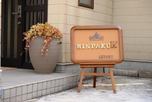 a sign on a stand next to two large vases at Minpaku-K in Nasushiobara