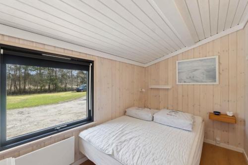 a small bedroom with a bed and a window at Cozy Summer House In North Jutland in Jerup