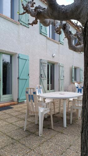 a table and two chairs sitting next to a tree at Villa du Moulin vers la Mer in Fleury