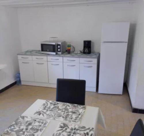 une cuisine avec une table et un comptoir avec un four micro-ondes dans l'établissement Gîte de la tuilerie, à La Celle-sous-Gouzon