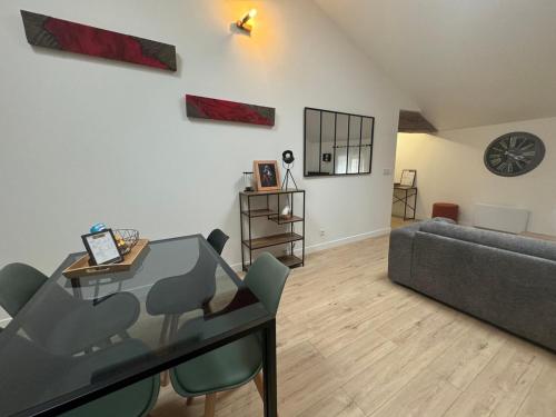 un salon avec une table en verre et un canapé dans l'établissement Appart'hotel Le clos des voyageurs - BY PRIMO C0NCIERGERIE, à Sennecey-le-Grand