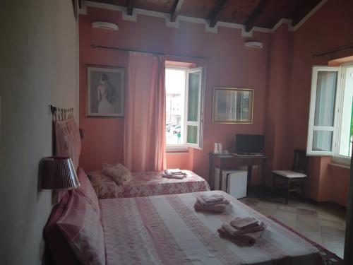 a bedroom with two beds and a desk and a window at B&B Guest House Il Porto Vecchio in Stintino