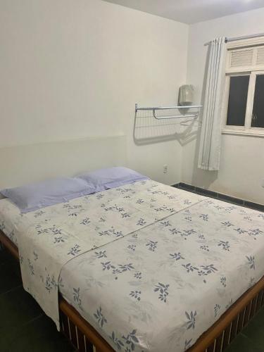 a bedroom with a bed with a blue and white comforter at CASA EM GUARAPARI in Guarapari
