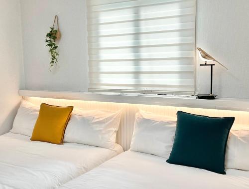 a white bed with two pillows and a window at Busan Vacance Stay, cozy house in Busan