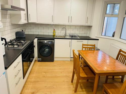 a kitchen with a table and a stove and a sink at OYO Dorset House at Upton Park in London
