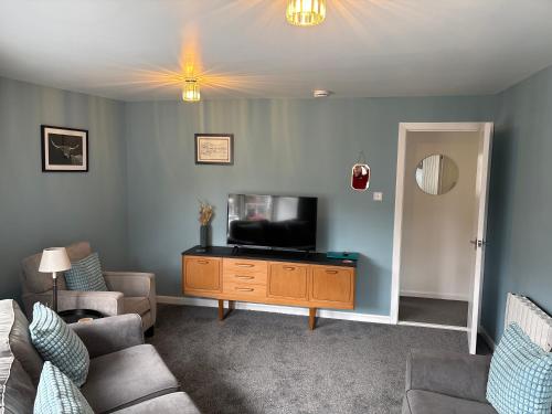a living room with a tv on a wooden dresser at 16 Macgregor court, Oban in Oban