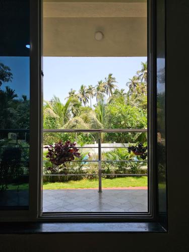 an open window with a view of palm trees at Oxygen Resort, Akshi in Alībāg