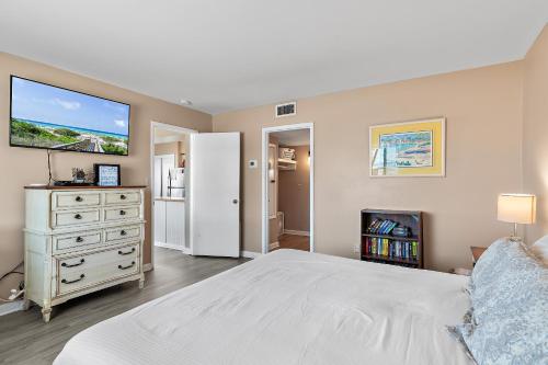 ein Schlafzimmer mit einem weißen Bett und einem TV an der Wand in der Unterkunft Capri by the Gulf 108 - Beachy Keen Bungalow in Destin
