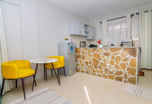 La cuisine est équipée d'une table, de chaises jaunes et d'un réfrigérateur. dans l'établissement Jay Homes - Rehema Apartments, à Naivasha
