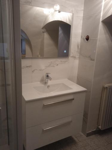 une salle de bain blanche avec un lavabo et un miroir dans l'établissement gite de la via ferrata liaucous, à Mostuéjouls