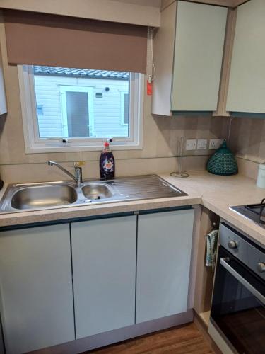 a kitchen with white cabinets and a sink and a window at Rockley Park Private Holiday Homes in Poole