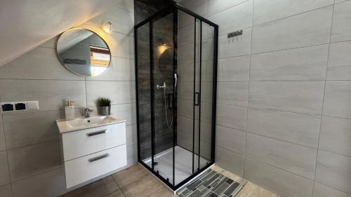 a bathroom with a shower with a sink and a mirror at Country House - apartamenty blisko Energylandii in Spytkowice