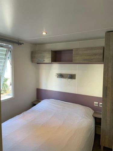 una camera da letto con un letto bianco e una finestra di Mobil-home 3 chambres, Plage & piscine, camping 4 étoiles a Torreilles
