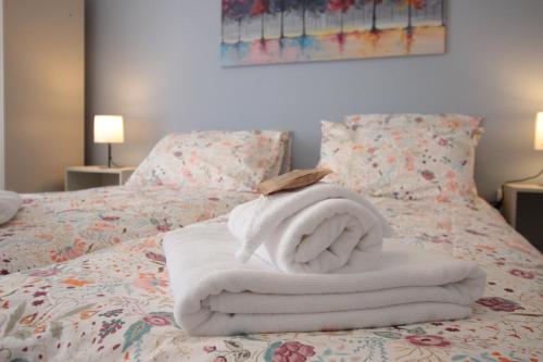 a pile of towels sitting on top of a bed at Les loges de Véro - Rez-de-chaussée - Parking privé - Garage vélo et moto - LOGEMENT NEUF - 5 couchages - 2 chambres - 1 canapé convertible - WIFI - Climatisation - Géré par Presta-Zen'Services in Thierville-sur-Meuse