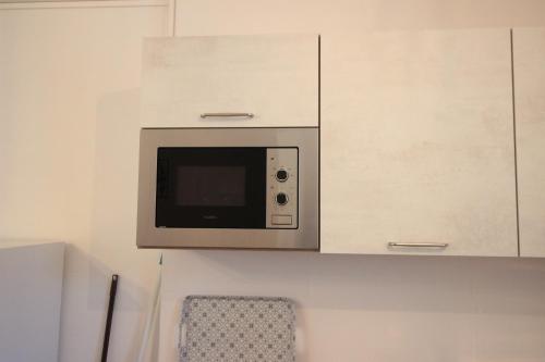 a microwave hanging from a cabinet in a kitchen at Les loges de Véro - Rez-de-chaussée - Parking privé - Garage vélo et moto - LOGEMENT NEUF - 5 couchages - 2 chambres - 1 canapé convertible - WIFI - Climatisation - Géré par Presta-Zen'Services in Thierville-sur-Meuse