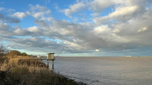 a dock on a body of water under a cloudy sky at Chez Christophe Pauillac chambre d'hôtes 1 chambre max 2 pers in Pauillac