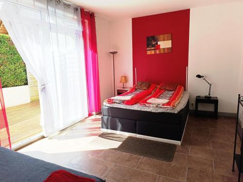 a room with a bed with a red wall at Grand Appartement 3 frontières in Hésingue