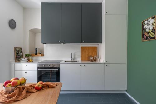 a kitchen with white cabinets and a bowl of fruit on a wooden table at Botanical by Tss - Nuovo, in centro, 10 min lago in Caldonazzo
