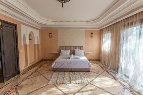 een slaapkamer met een bed en een groot raam bij Villa Dahlia in Marrakesh