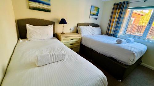 two twin beds in a room with a window at Family Friendly Lodge sleeping 5 with Hot Tub - Devon in Chudleigh