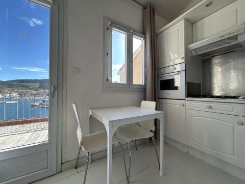 une table blanche et des chaises dans une cuisine avec une fenêtre dans l'établissement Studio 2-4 pers avec terrasse et vue mer, Port-Vendres, calme, proximité centre - FR-1-225C-7, à Port-Vendres