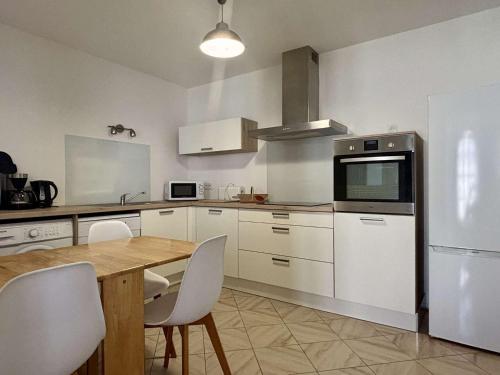 une cuisine avec une table en bois et des appareils électroménagers blancs dans l'établissement Élégant T2 avec Jardin, Secteur Calme, Proche Mer et Commerces - Latour-Bas-Elne - FR-1-225-650, à Latour-Bas-Elne