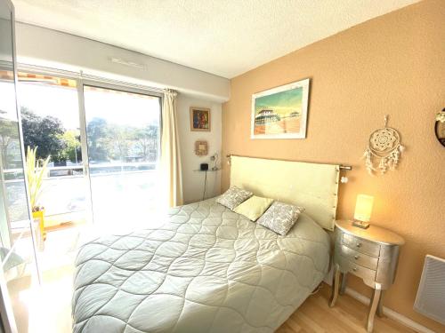 une chambre avec un lit et une grande fenêtre dans l'établissement T2 Moulleau centre parking, clim, wifi,C229, à Arcachon