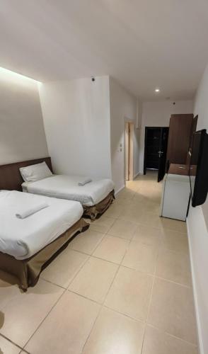 two beds in a room with a tiled floor at New Metropole Hotel - Jerusalem in Jerusalem