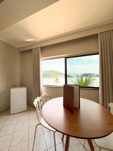 a dining room with a table and a large window at Ilha Porchat Hotel in São Vicente