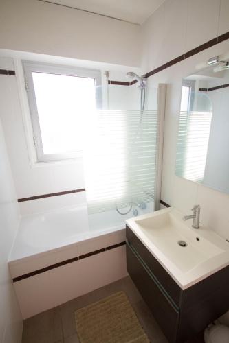 une salle de bain blanche avec un lavabo et une fenêtre dans l'établissement Appartement et terrasse Port du Pouliguen, au Pouliguen