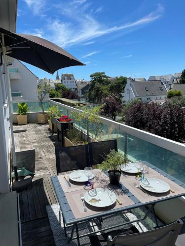 une table à manger sur un balcon avec un parasol dans l'établissement Appartement et terrasse Port du Pouliguen, au Pouliguen
