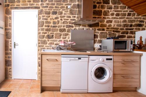 a kitchen with a washing machine and a microwave at La Mancellière de Montjoie chambres d'hôtes et gîtes in Saint-Michel-de-Montjoie