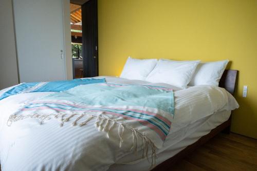 a bed with white sheets and pillows in a bedroom at ViLLA SHiNAHA ヴィラシナハ 与論島 in Yoron
